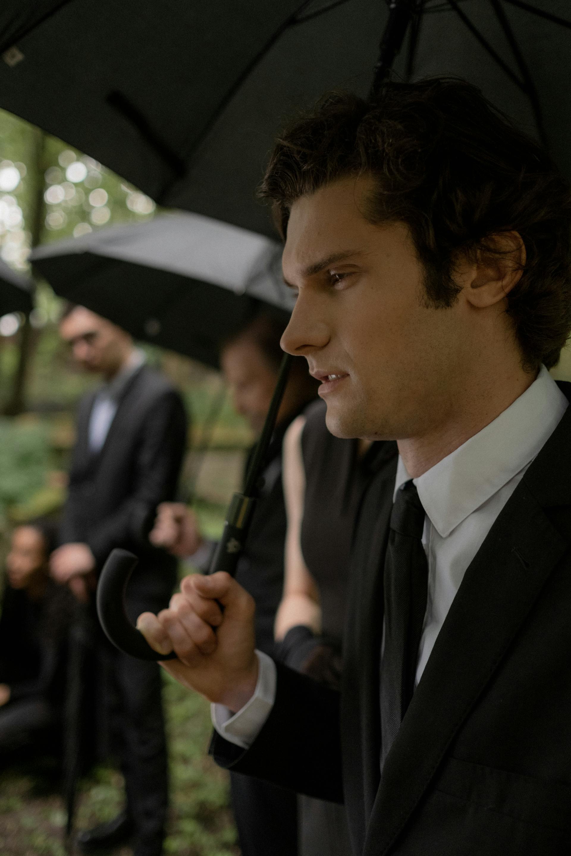 Close-up of a man holding an umbrella while attending a funeral | Source: Pexels