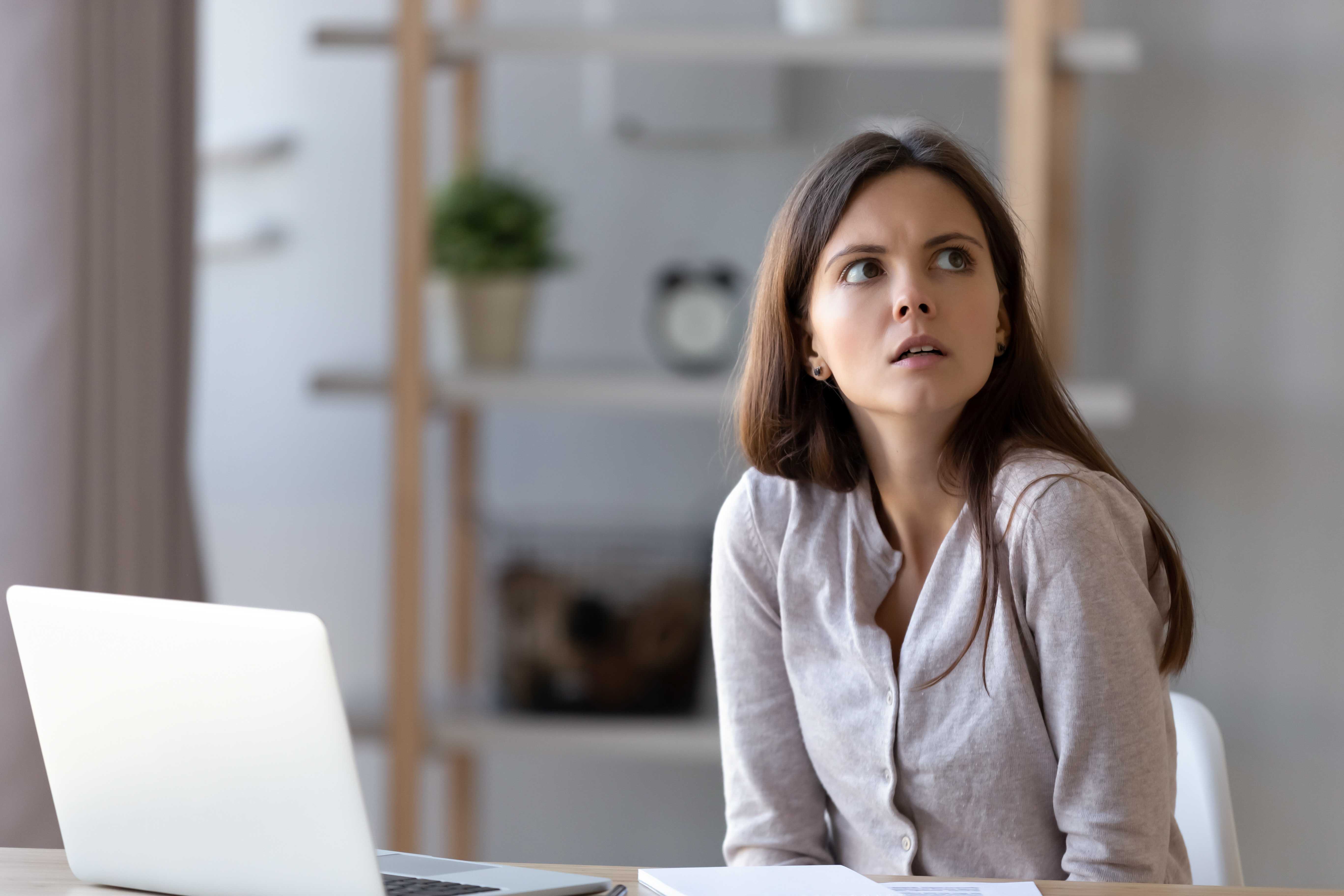 A young woman looking up and away from a laptop | Source: Shutterstock