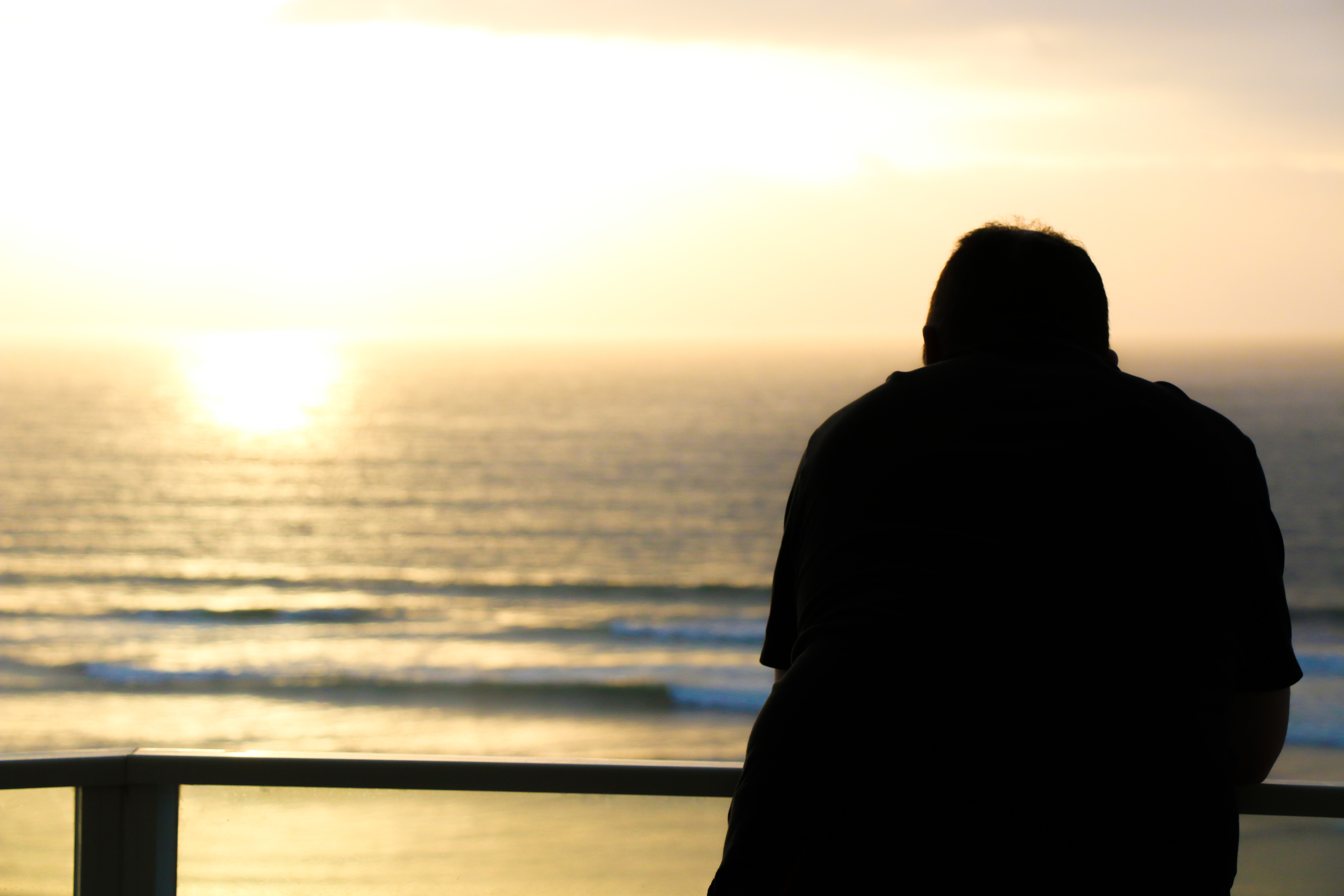 Man looking out a balcony at sea | Source: Shutterstock