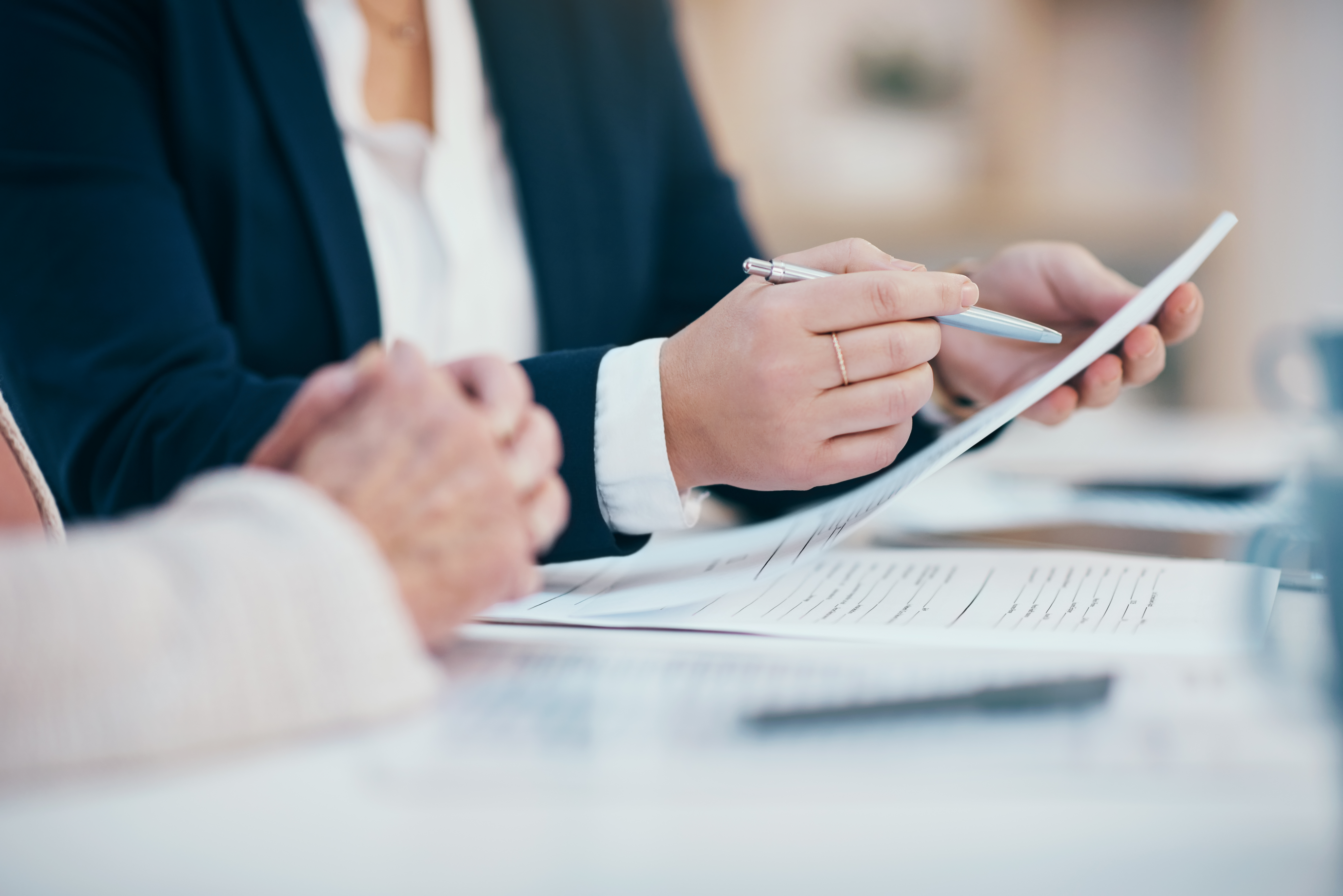 Hands closeup on contact, legal settlement or financial report while reading and making notes. Lawyer team doing work and analyzing documents. Lawyers looking through client finance data together | Source: Getty Images