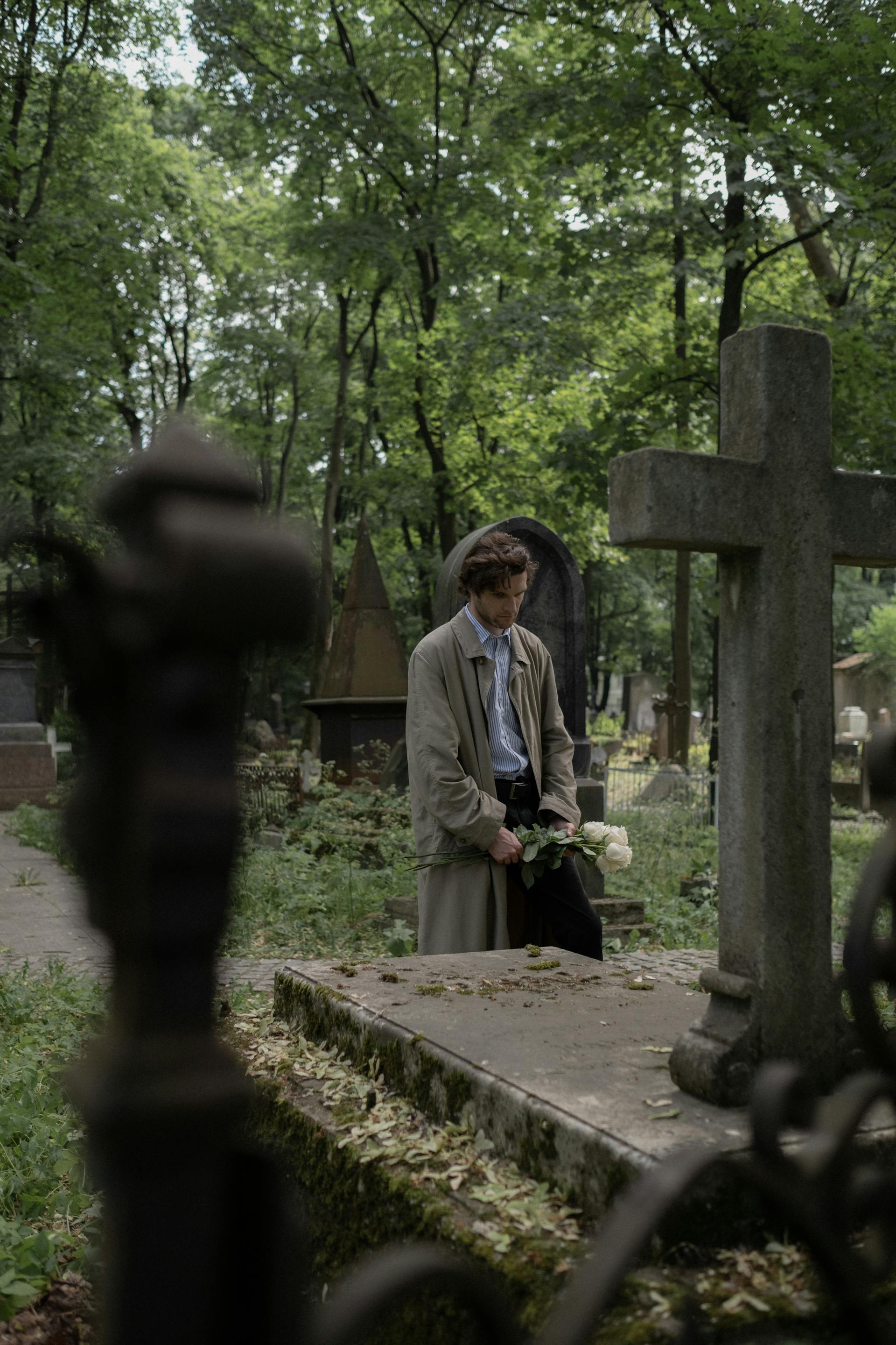 A man standing in front of a loved one's grave in a cemetery | Source: Pexels