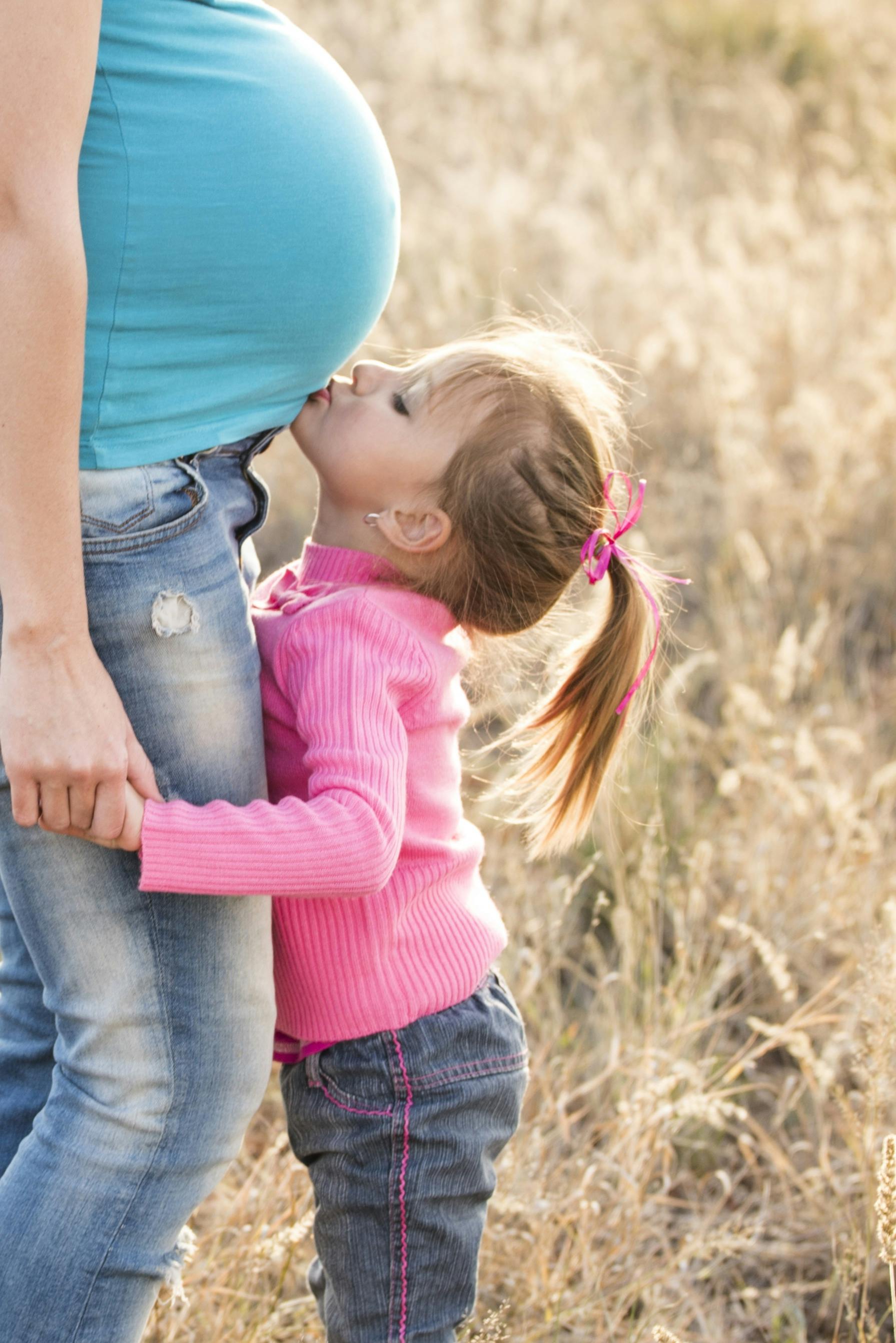 A woman's daughter kissing her pregnant belly | Source: Pexels